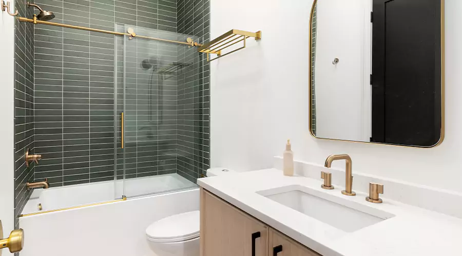 Modern bathroom remodel featuring light wood vanity, black floor tile, and tub-shower combo with sliding glass doors